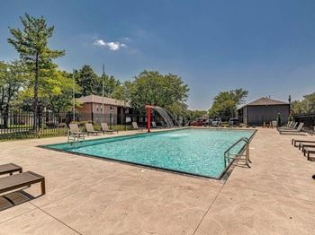 A large outdoor swimming pool surrounded by a fence and trees.